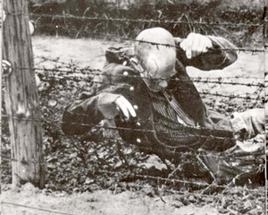The body of an inmate sits motionless in death after committing suicide on an electrified fence at Auschwitz.